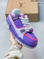 Angled side view of the purple and pink Trainer Maxi Low sneaker showing the layered panels, branded side strap, white laces, and patterned outsole.
