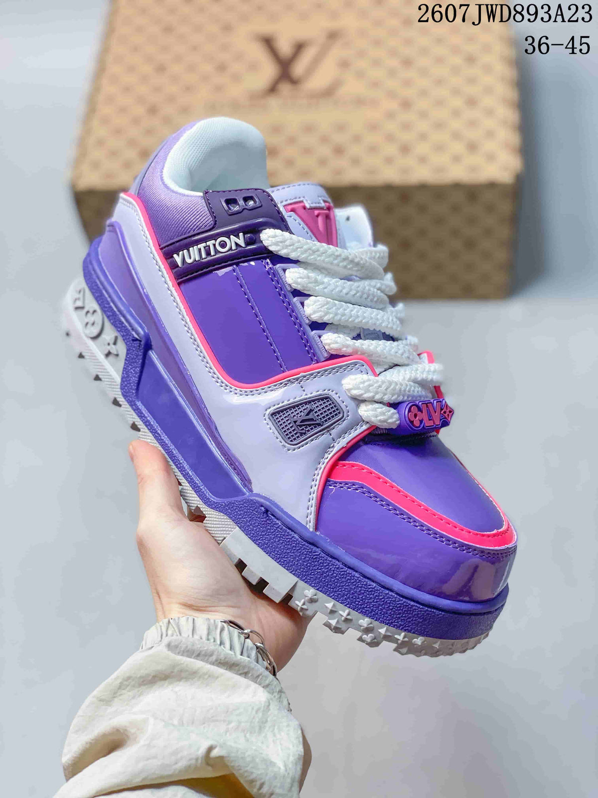 Angled side view of the purple and pink Trainer Maxi Low sneaker showing the layered panels, branded side strap, white laces, and patterned outsole.