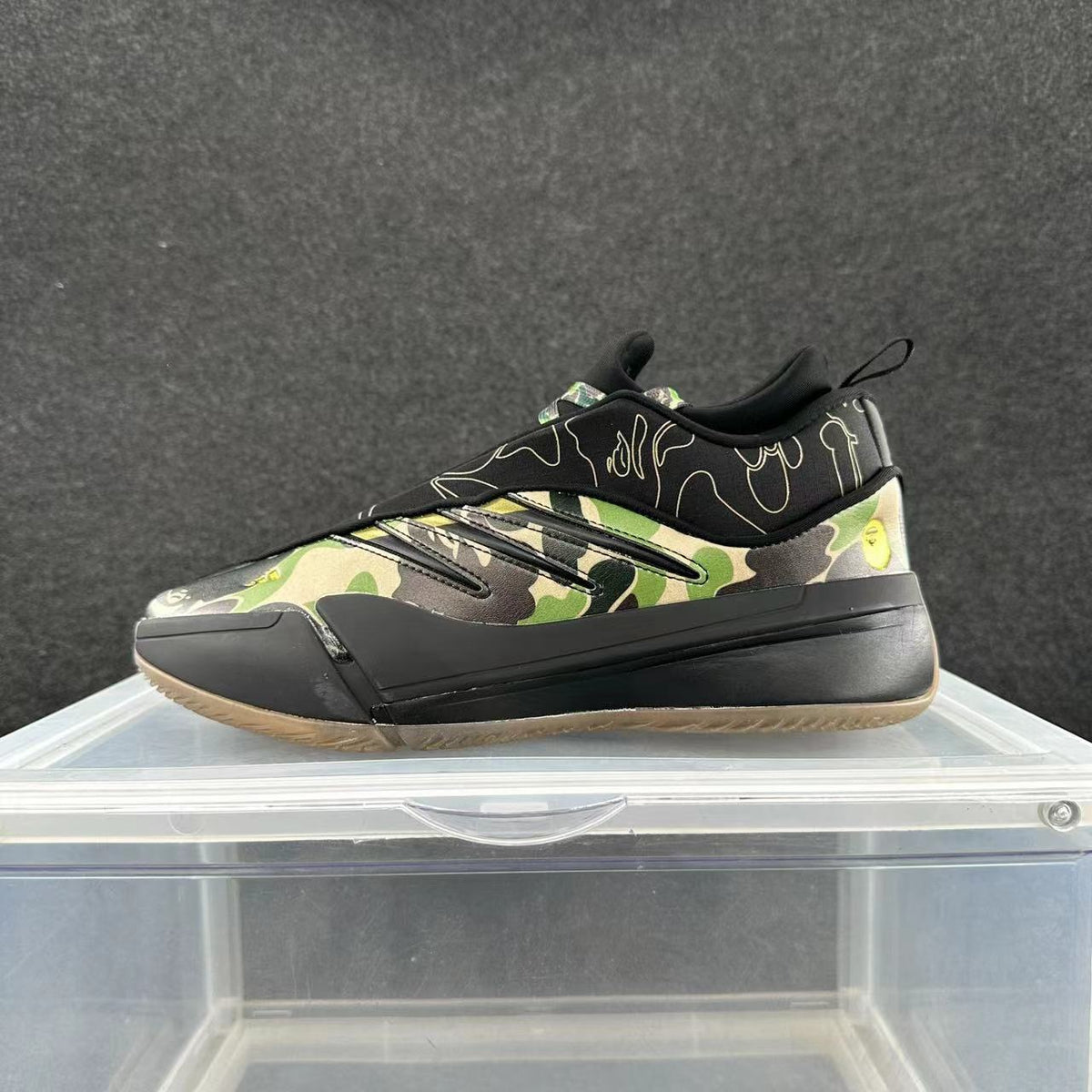 Side view of low-top sneakers with green, tan, and black camouflage panels, a black collar and sole, and a gum-colored outsole.