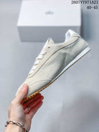 Side view of the light beige sneaker showing perforated detailing, stitched panels and a white midsole.