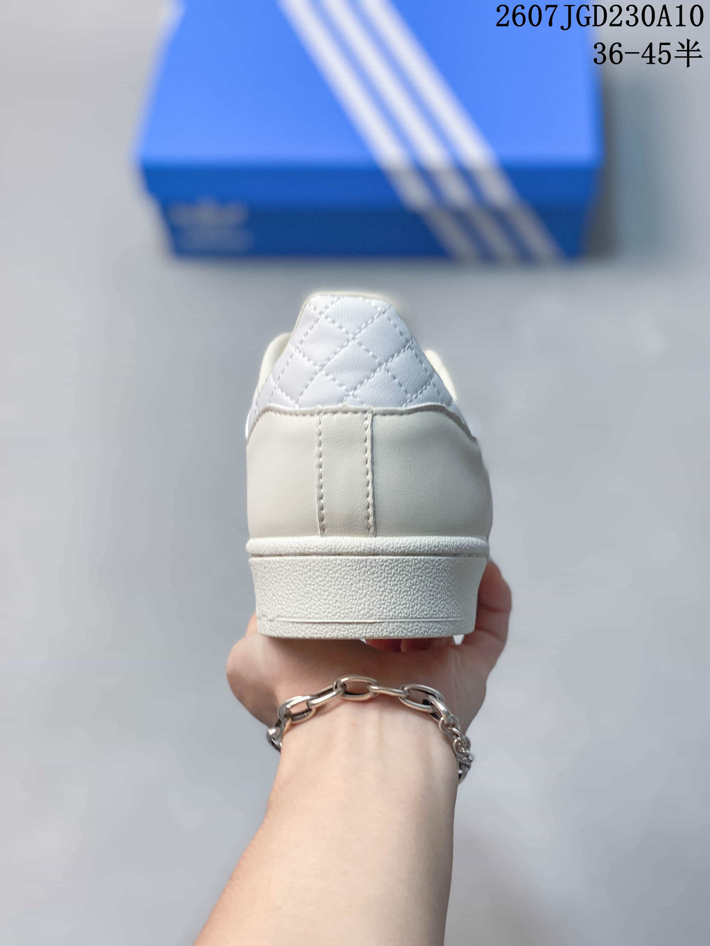 Rear view of the white sneaker showing the padded collar, stitched heel panel, and textured midsole.