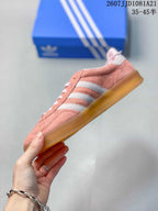 Side profile showing the pink upper, white stripes and low-profile gum sole.