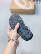 Close view of the dark patterned outsole and segmented tread on an ASICS HYPERSYNC kids’ sneaker.