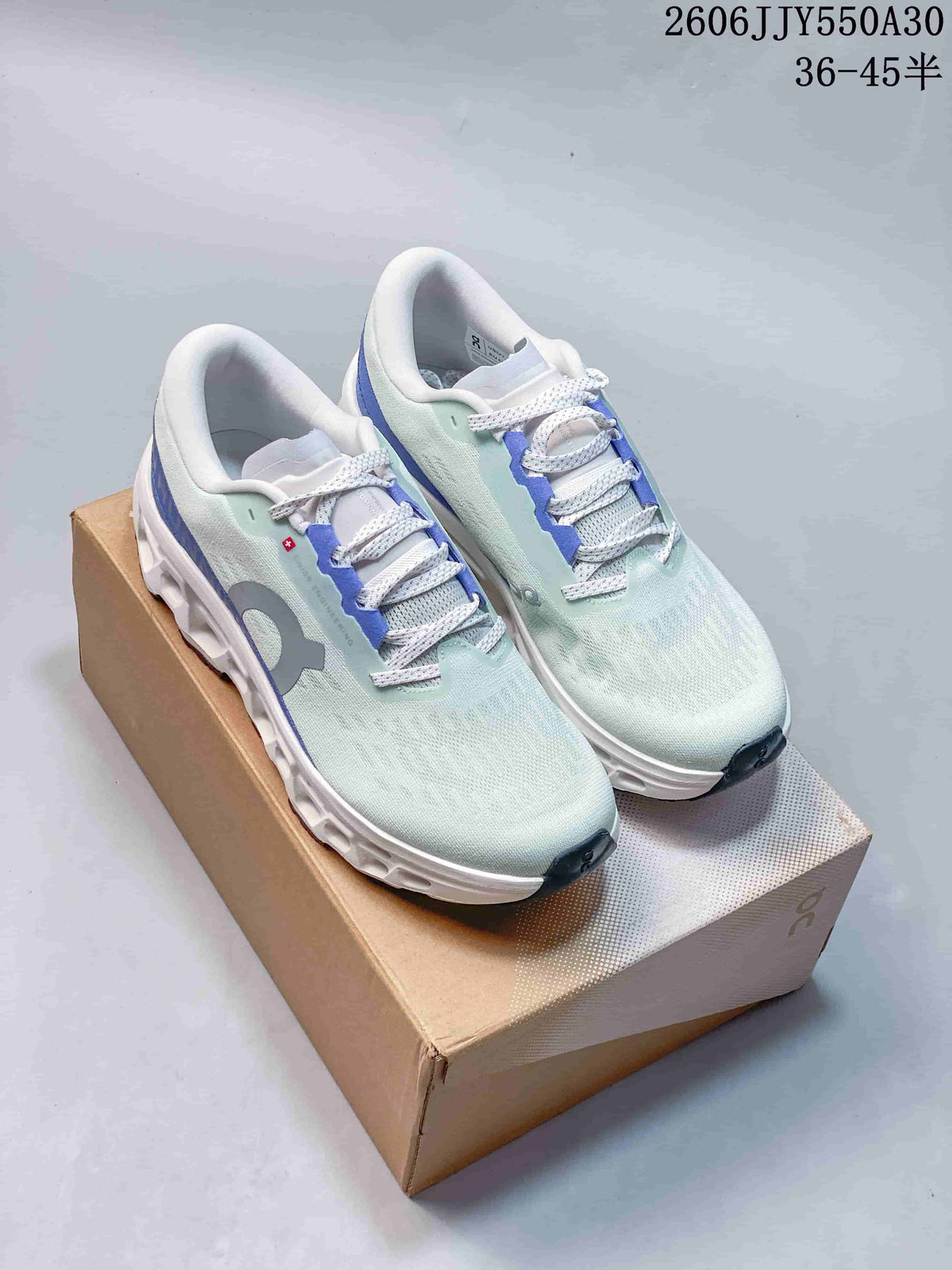 Pair of pale mint and blue On Cloudmonster 3 running shoes on a shoebox