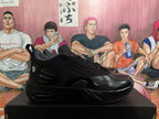Side profile of a black Jordan sneaker with layered textured and glossy panels, padded collar, and visible air-style heel window.