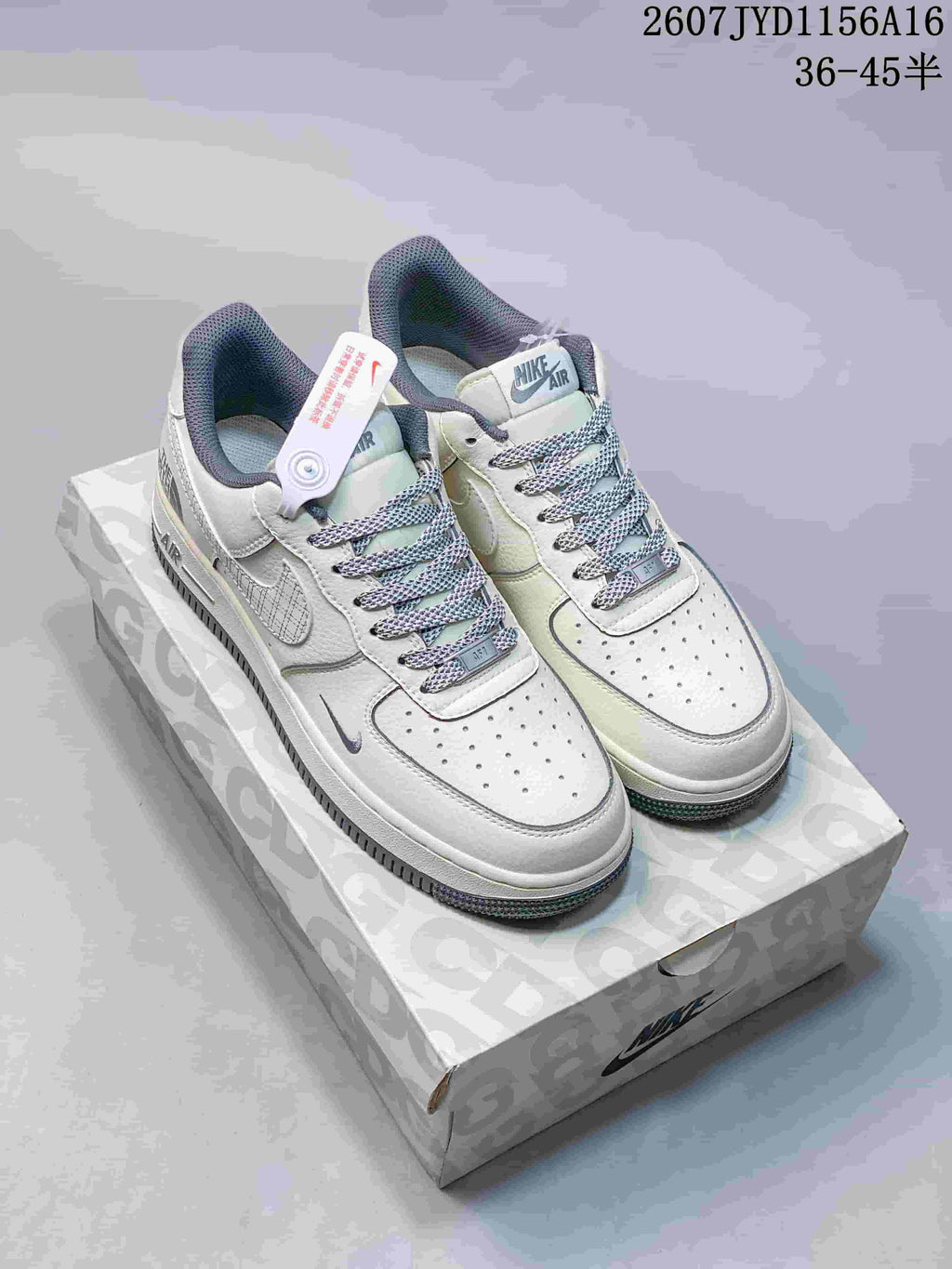White low-top sneakers with pale grey Swoosh details, patterned laces, and contrasting outsole displayed on a printed shoe box.