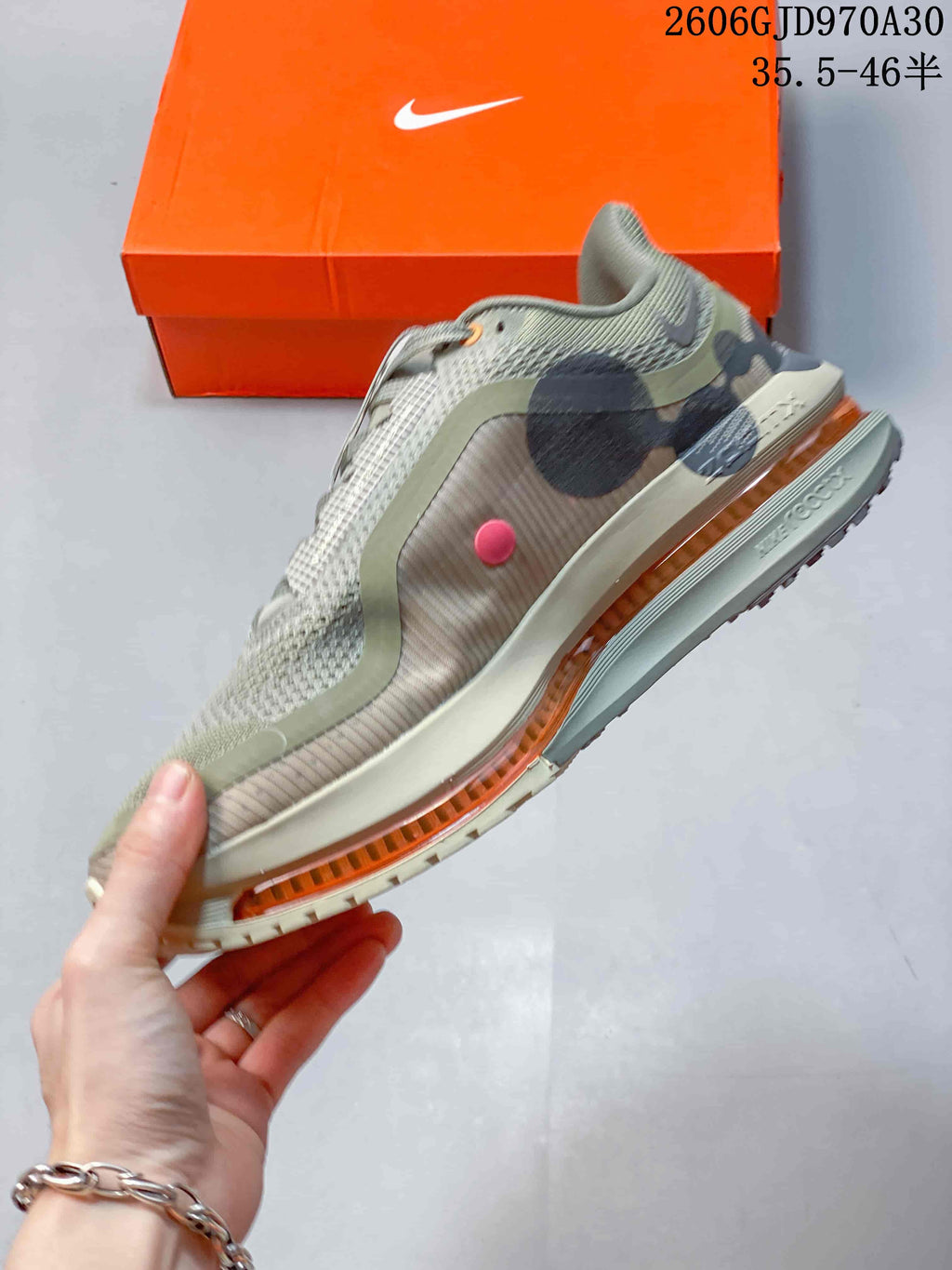 Side profile showing the olive-grey upper, dark overlays, and orange cushioning element.