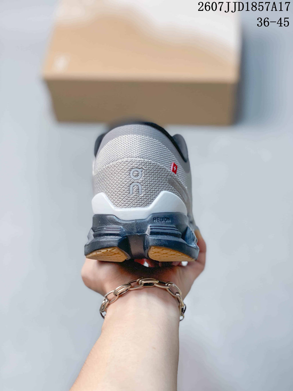Rear view of a gray sneaker showing the On logo, dark heel structure, and segmented outsole.