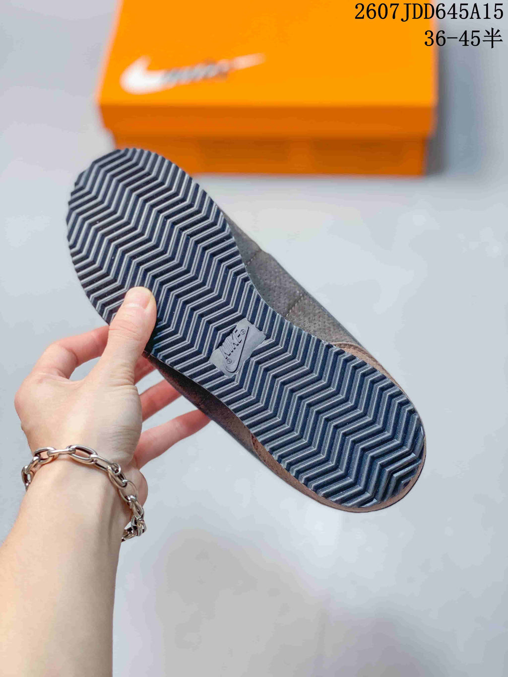 Close-up of the sneaker outsole showing a repeating zigzag tread pattern and an orange shoe box in the background.