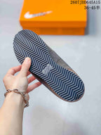 Close-up of the sneaker outsole showing a repeating zigzag tread pattern and an orange shoe box in the background.