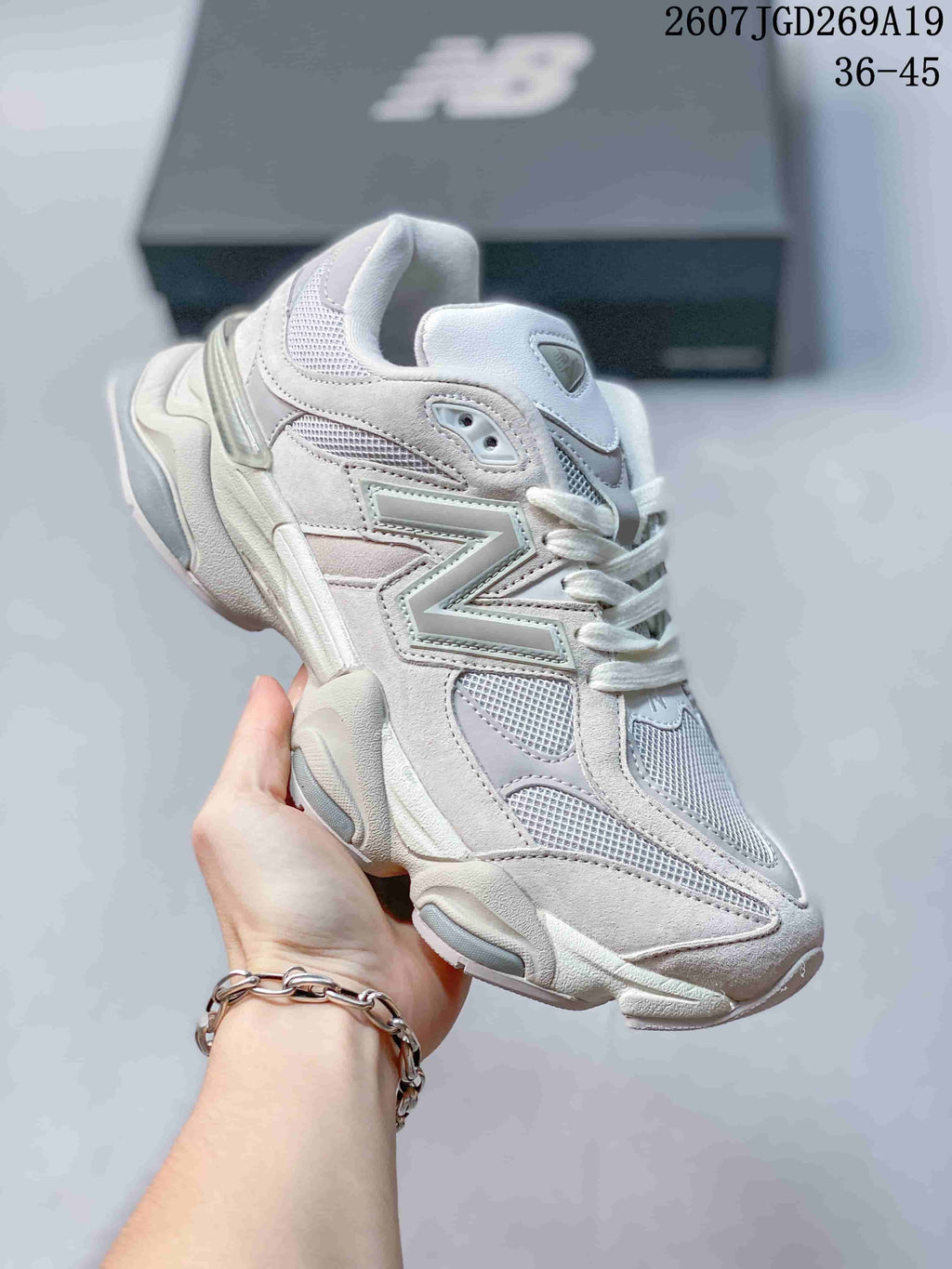 Angled side view of a light white New Balance 9060 sneaker showing the New Balance side logo, mesh panels and layered sole.