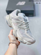 Angled side view of a light white New Balance 9060 sneaker showing the New Balance side logo, mesh panels and layered sole.