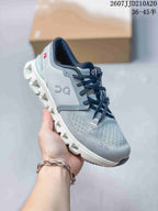 Angled side view showing the gray and pale mint-green colorway, black laces, and white segmented outsole.