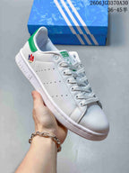 Angled view of the white sneaker with green accents and perforated side panels