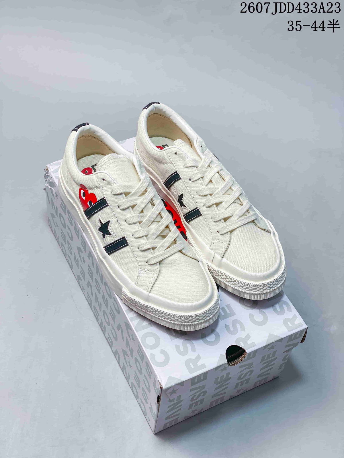 Pair of off-white low-top sneakers with dark side stripes and star details displayed on a Converse-patterned box.