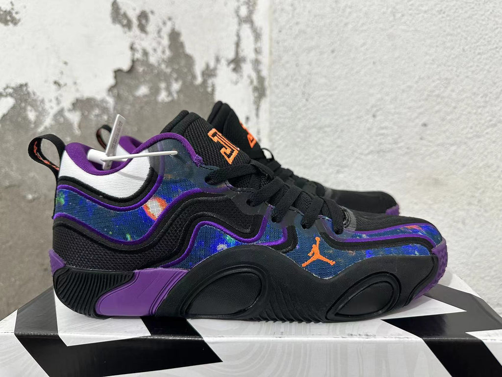 Side view of a black Jordan basketball shoe with purple trim, multicolor patterned panels, and an orange Jumpman logo.