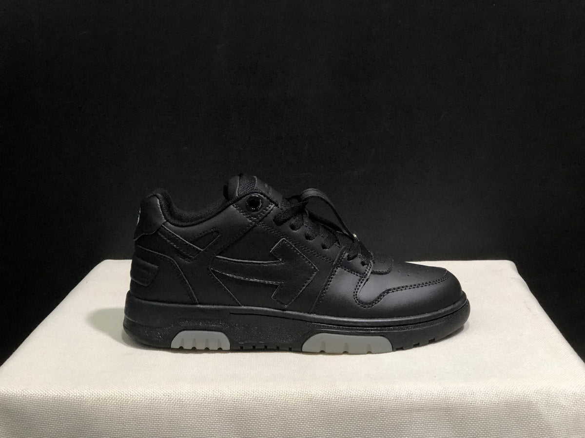 Side profile of a black low-top sneaker showing the lace-up upper, layered side detailing and segmented light outsole sections.