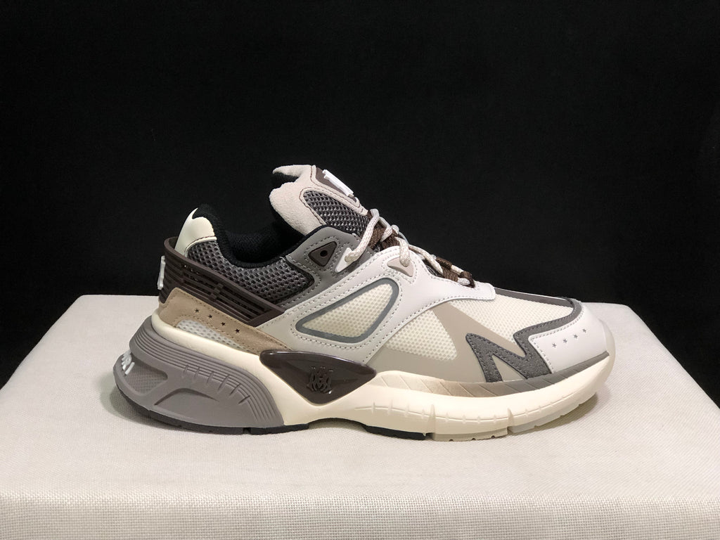 Side view of the off-white and grey AMIRI MA Runner sneaker with layered panels and a chunky outsole.