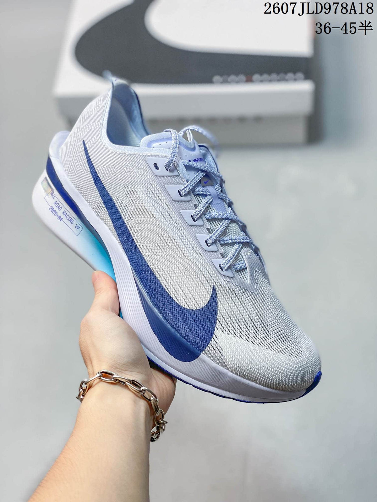 Light-colored Nike racing sneaker with blue side branding and blue sole accents; image text shows style code 2607JLD978A18 and size range 36–45.