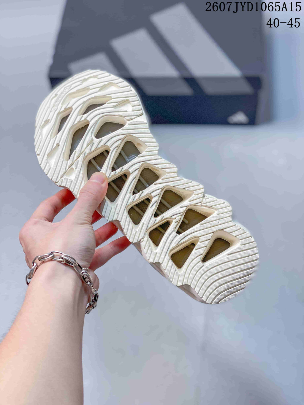 Close view of the sneaker outsole showing the sculpted tread pattern and open geometric sections, with style code JYD1065A15 and size range 40–45 visible.