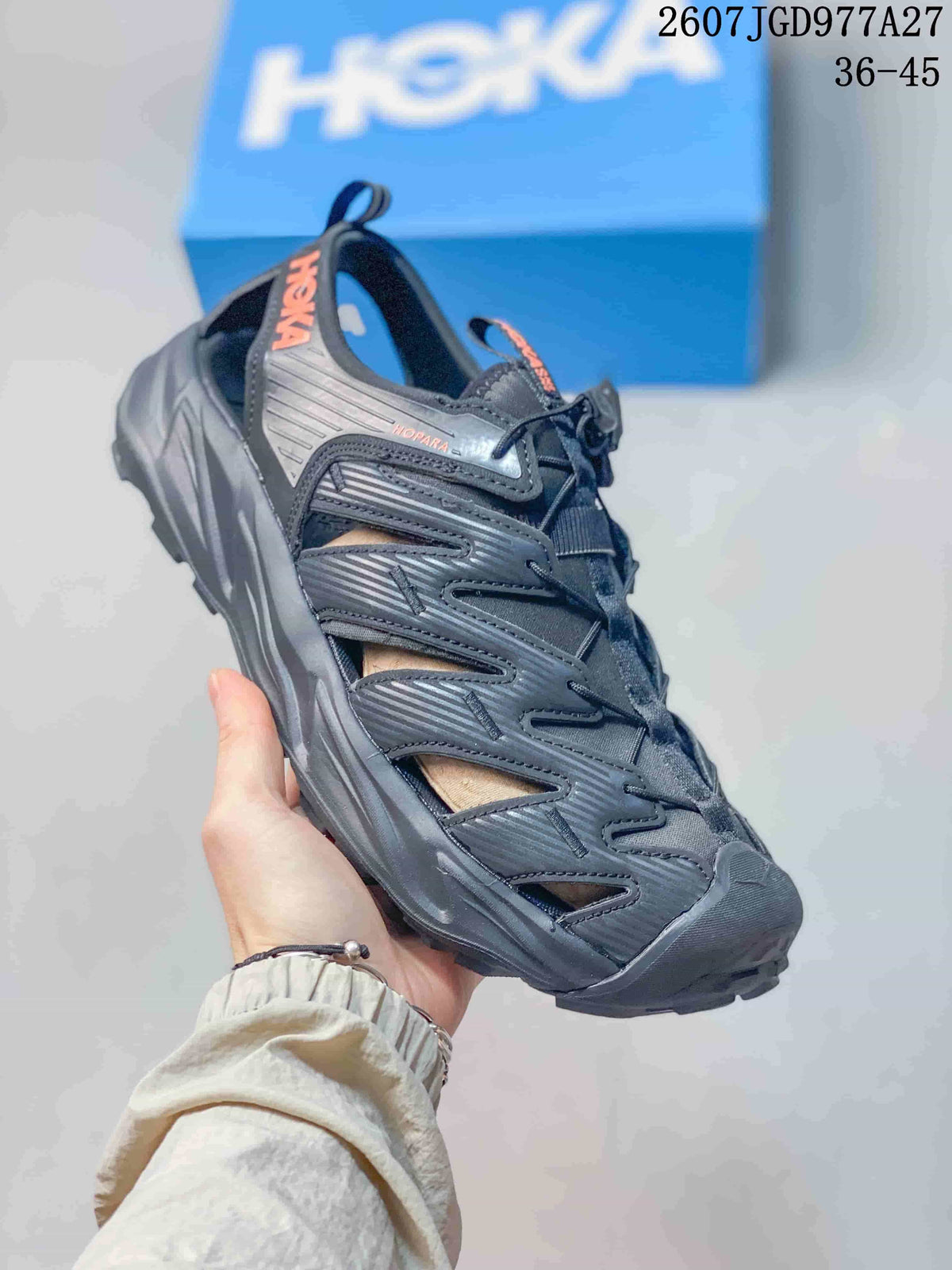 Angled side view of a black HOKA Hopara OG sandal showing HOKA branding, Hopara detailing, toggle lacing and rugged outsole.