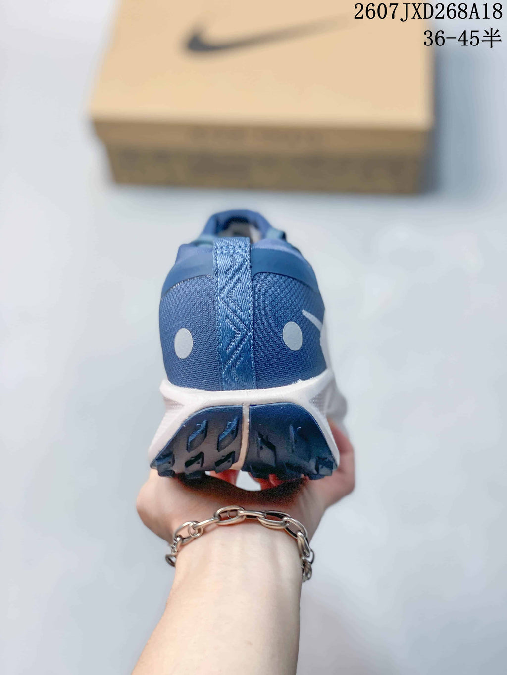 Rear view of the blue sneaker showing the heel pull tab, reflective circular details, and split outsole pattern.