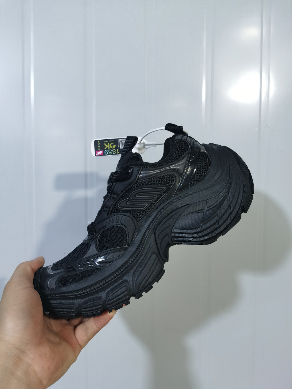 Opposite angled view of the black sneaker showing the mesh upper, padded collar, lace area, and textured outsole.