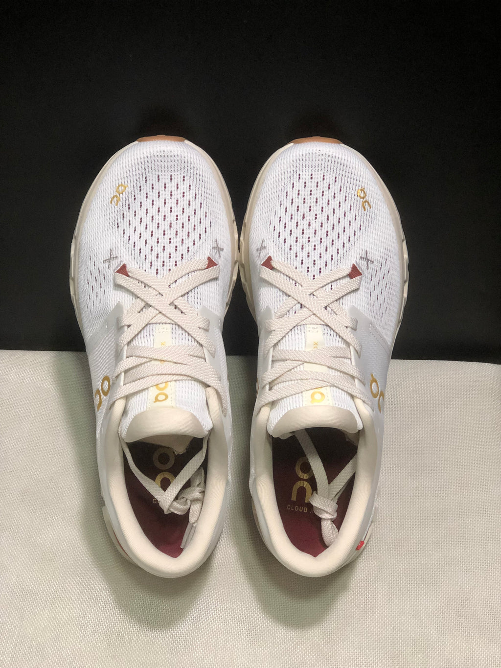Top-down view of the white On Cloud X4 pair showing the lace-up closure and perforated toe panels.