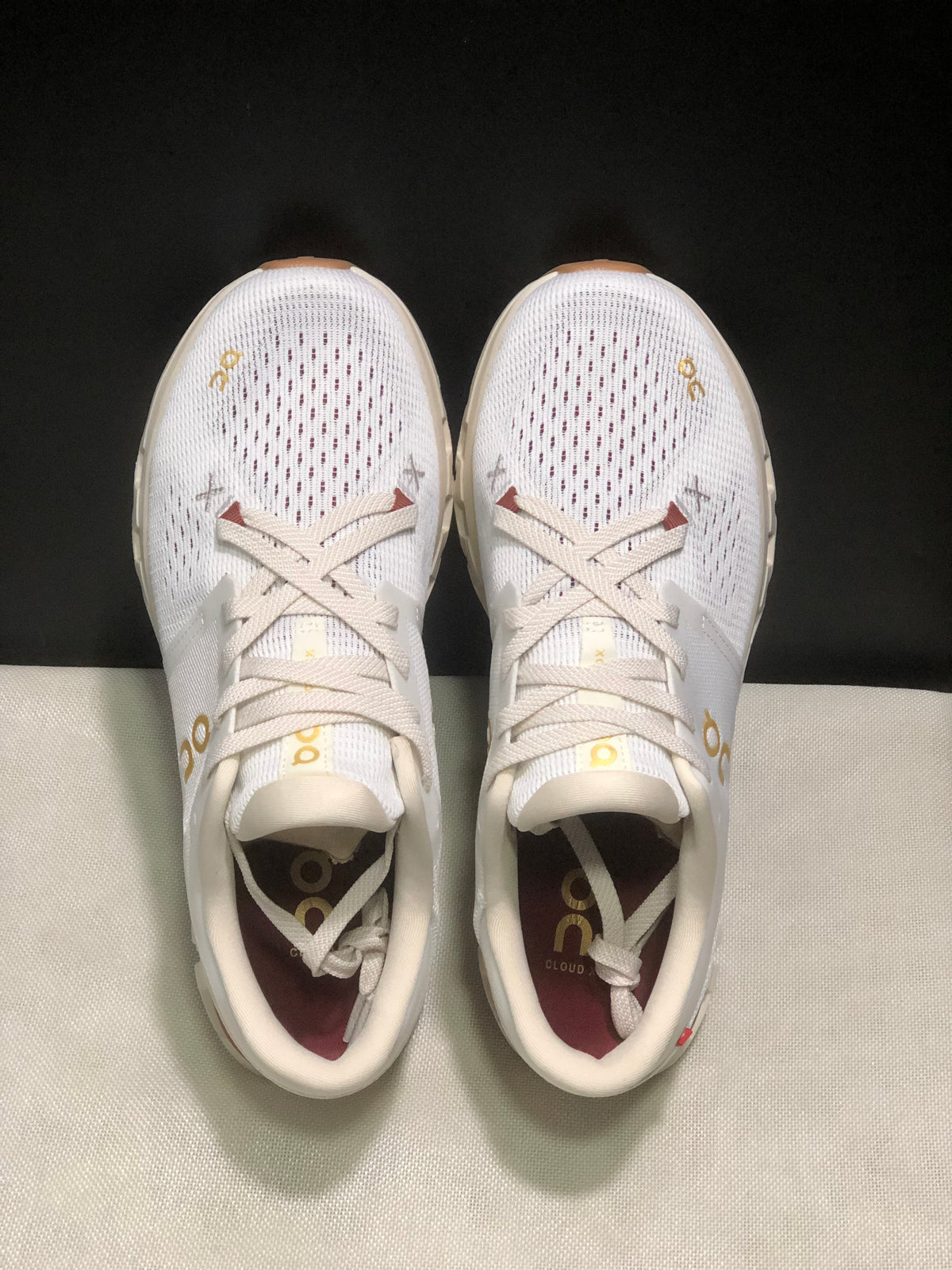 Top-down view of the white On Cloud X4 pair showing the lace-up closure and perforated toe panels.