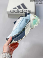 Side view showing the pale blue upper, layered side panels, navy midsole section and cream outsole.