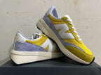 Angled view of yellow, white, and lavender New Balance U370 sneakers
