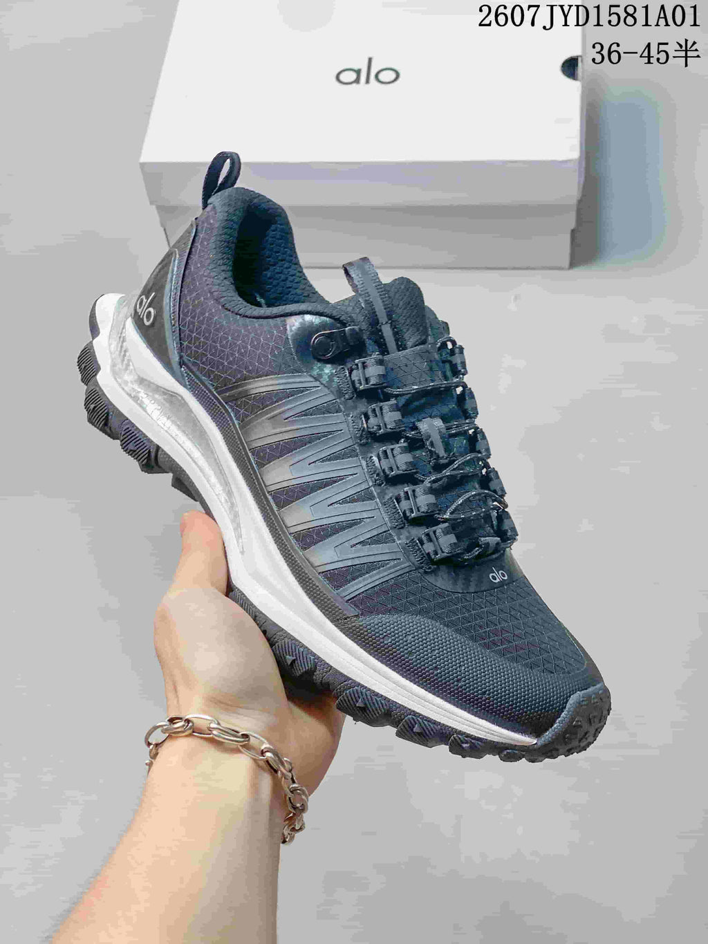 Close-up of a black Alo Trail sneaker showing its lace-up fastening and layered side panels.