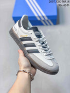 Angled side view showing the white and gray upper, dark stripes, heel text, and textured sole.