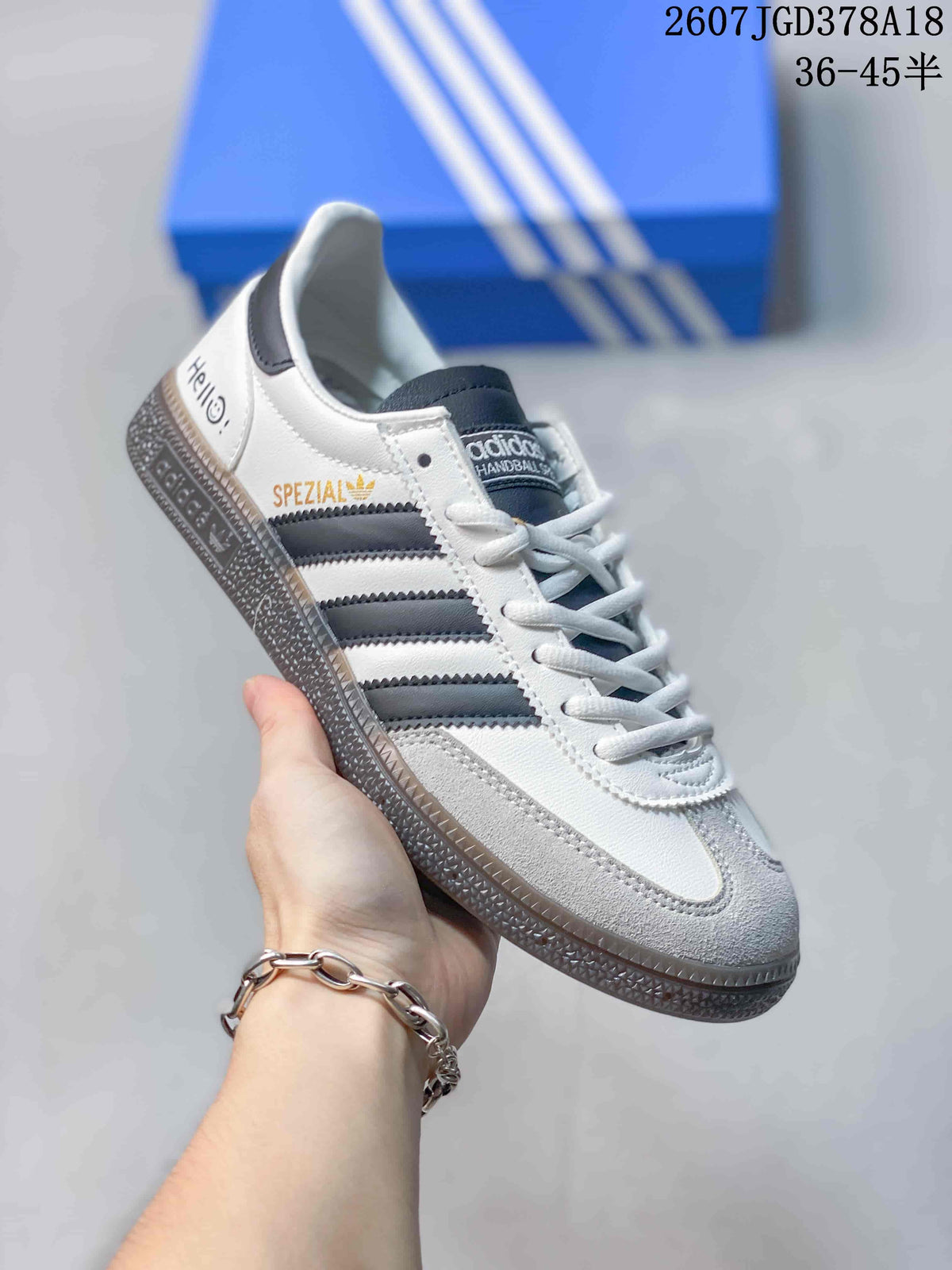 Angled side view showing the white and gray upper, dark stripes, heel text, and textured sole.