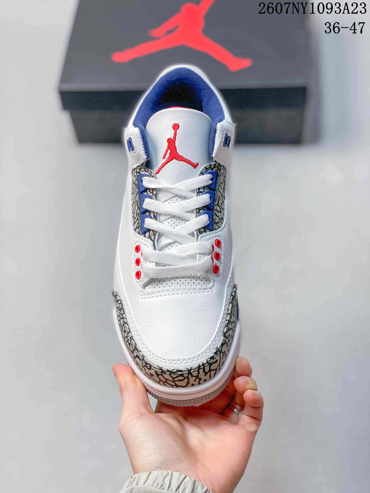Top view showing white laces, red tongue branding, blue eyestay details, and elephant-print side panels.