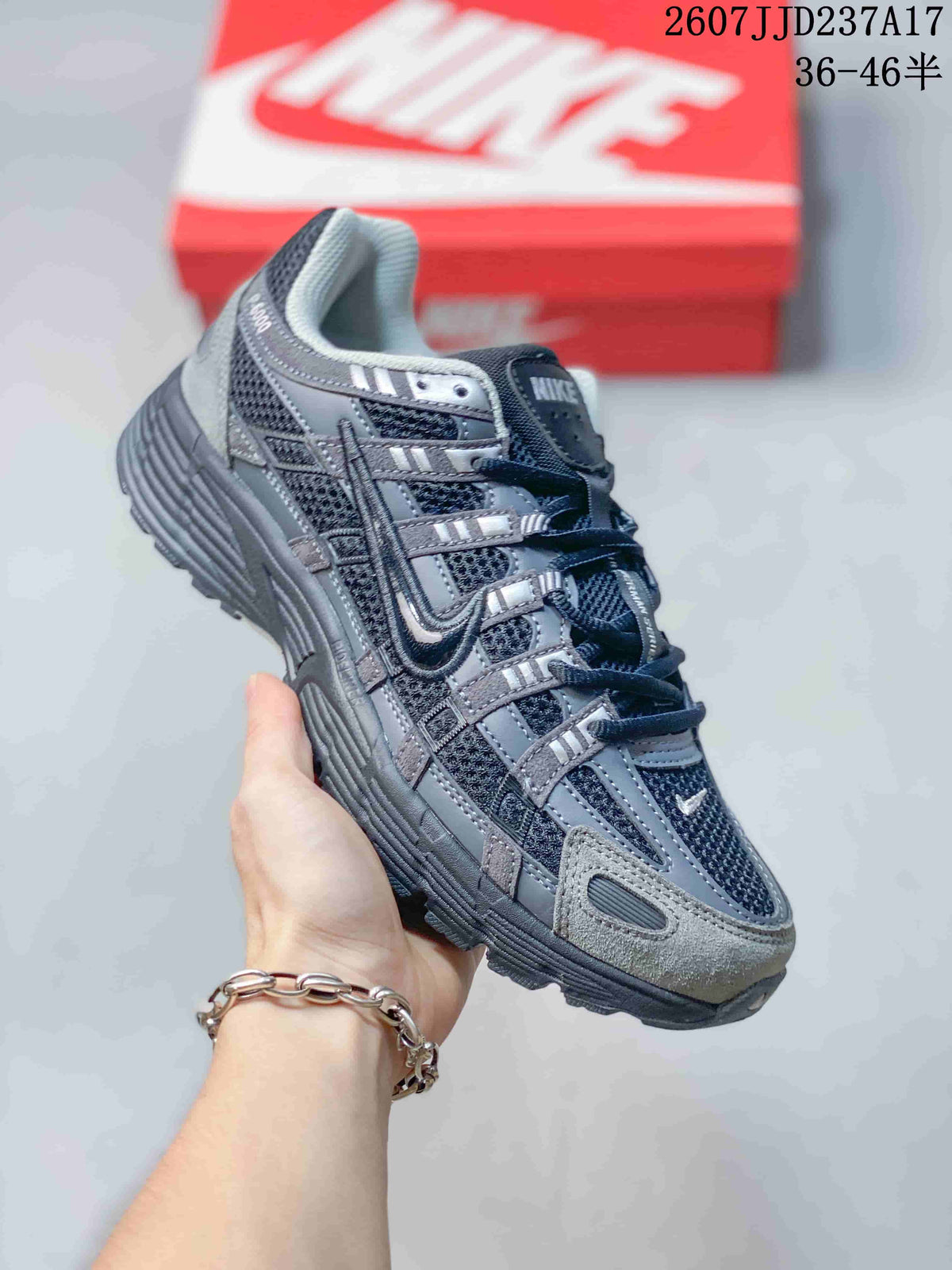 Angled side view of the gray and black Nike P-6000 sneaker showing the layered upper, mesh panels, lace system, and textured sole.