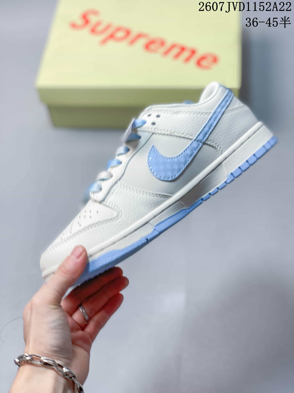 Side view showing the white layered upper, light blue Swoosh, laces, midsole, and outsole.