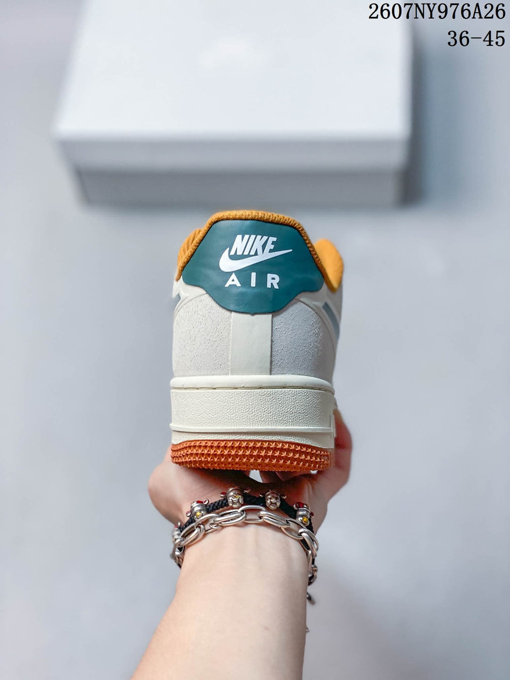 Rear view of the sneaker showing the white heel, teal-and-white heel tab, orange collar lining, and orange outsole.