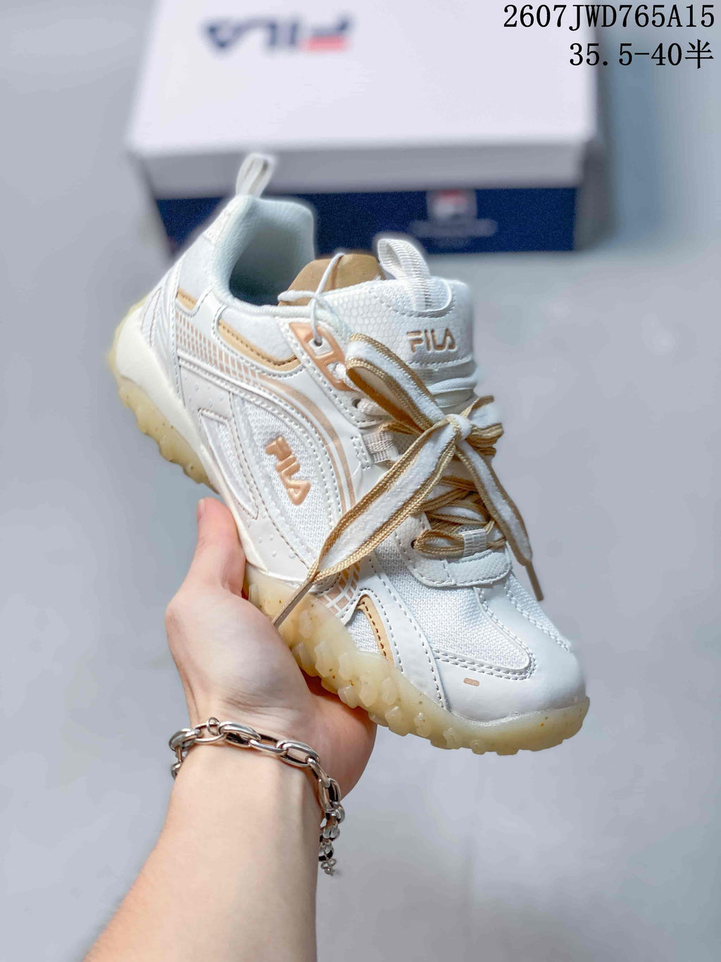 Angled side view of the white and gold FILA Pebble sneaker showing its low-top shape and textured outsole.