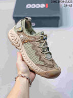 Three-quarter side view of the beige and muted green sneaker with mesh panels, pull tabs, and rugged outsole.