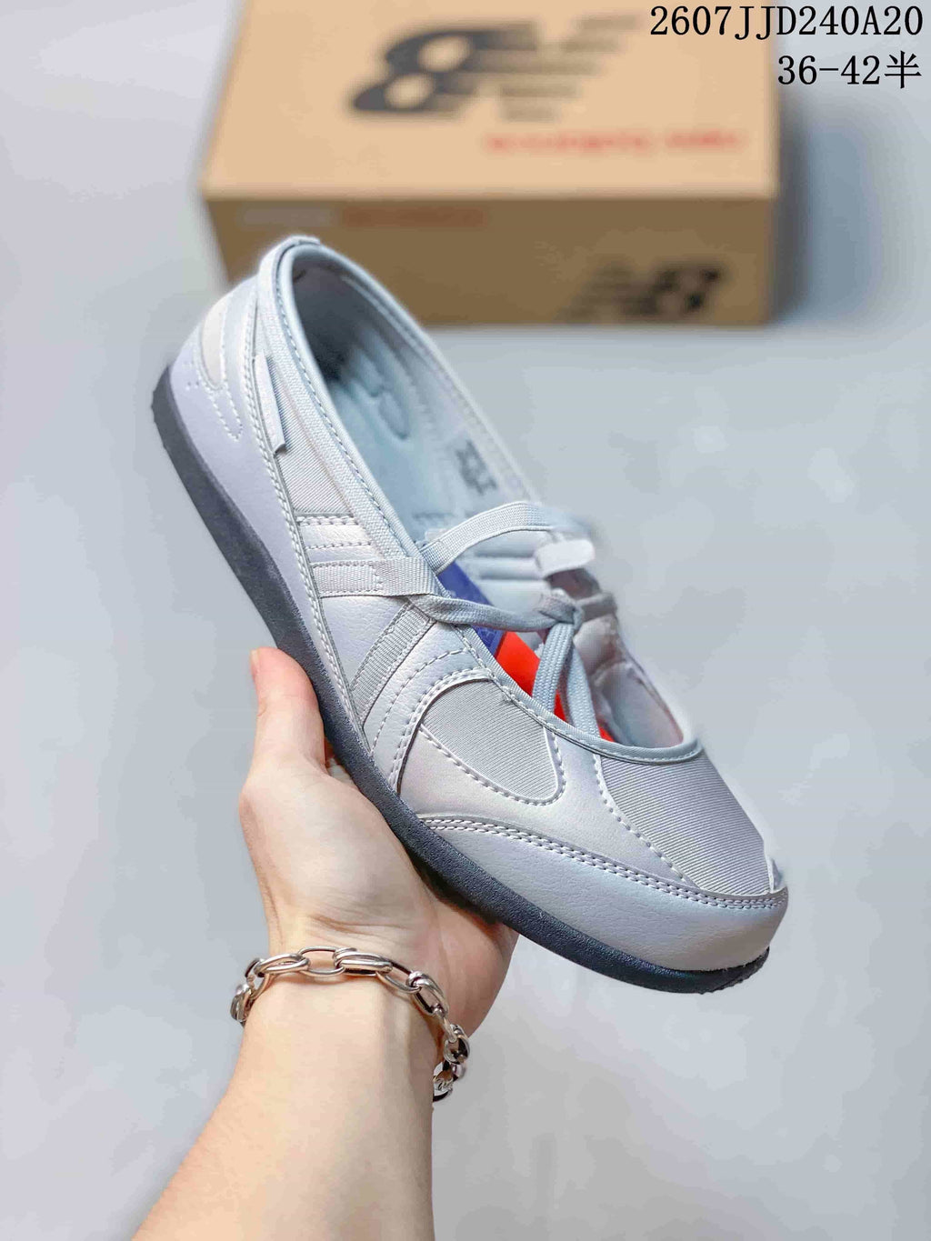 Side view of a grey New Balance Flat Breeze shoe showing the layered upper, lace-up front, and dark outsole.