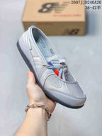 Side view of a grey New Balance Flat Breeze shoe showing the layered upper, lace-up front, and dark outsole.