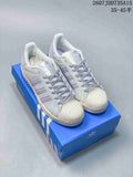 Pair of white and lavender adidas Superstar sneakers displayed on a blue shoebox.