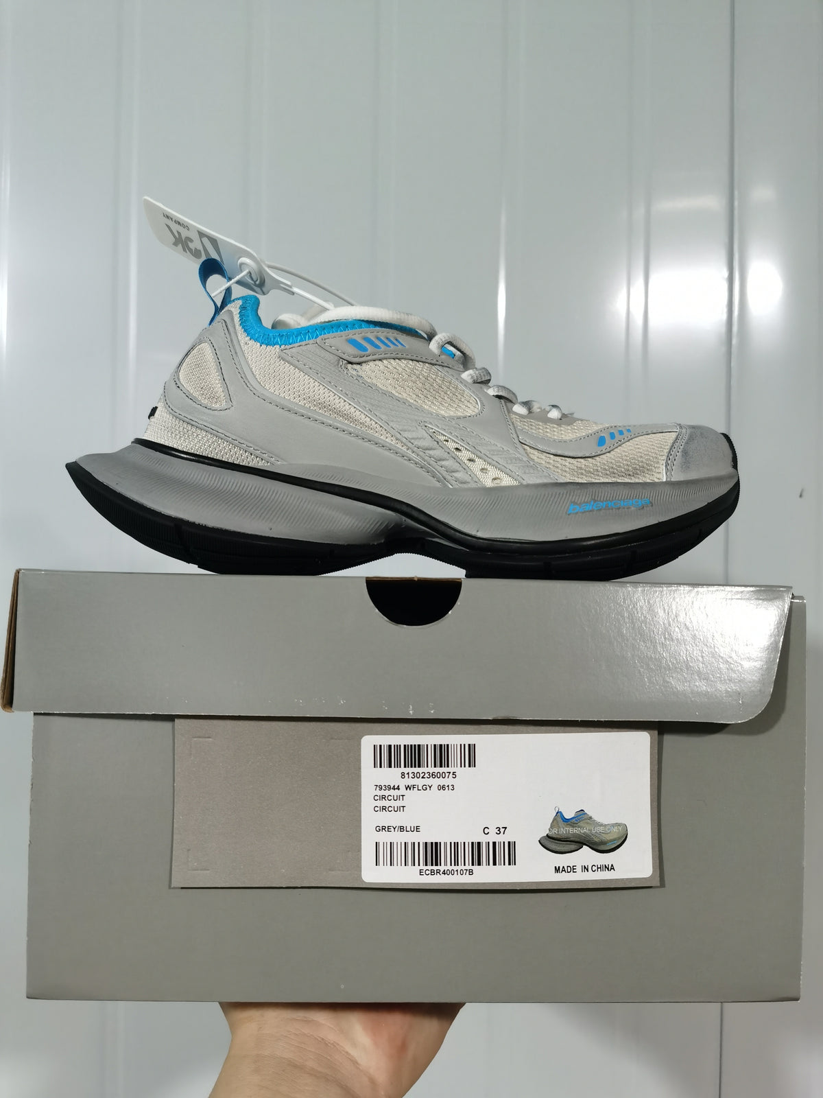 Side profile of the sneaker resting on its box; the box label shows Circuit, Grey/Blue, and size C 37.