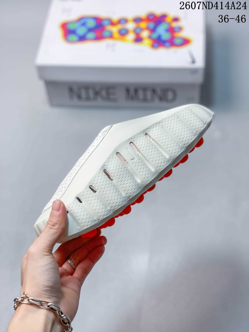 Side and outsole view of the white clog, showing perforations, sculpted sidewalls, and orange outsole pods.