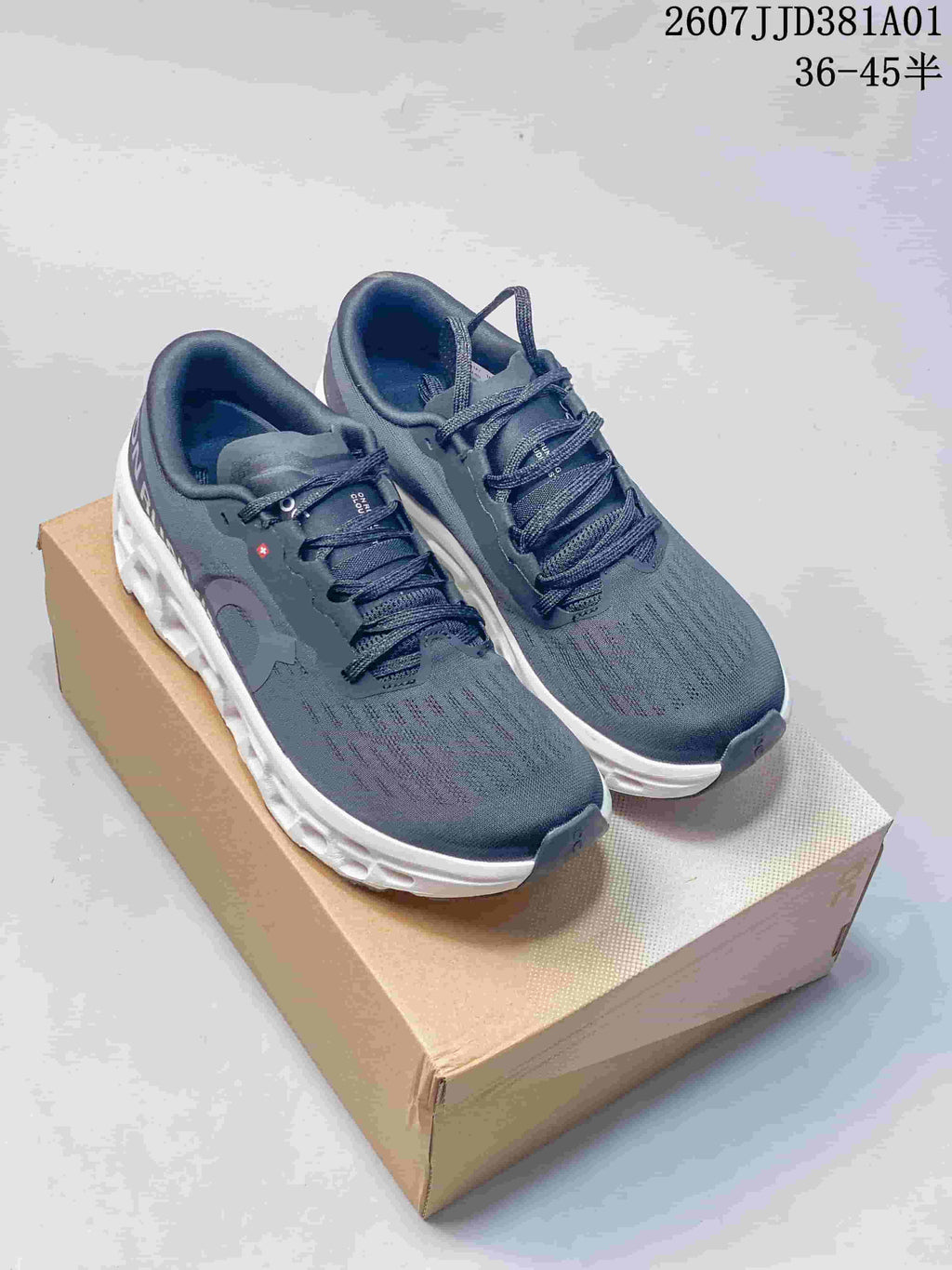 Pair of dark navy and gray On Cloudmonster 3 LightSpray shoes on a box, viewed from above and at an angle.