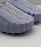 Close-up of the perforated strap, textured upper, and scalloped edge of the purple slide.