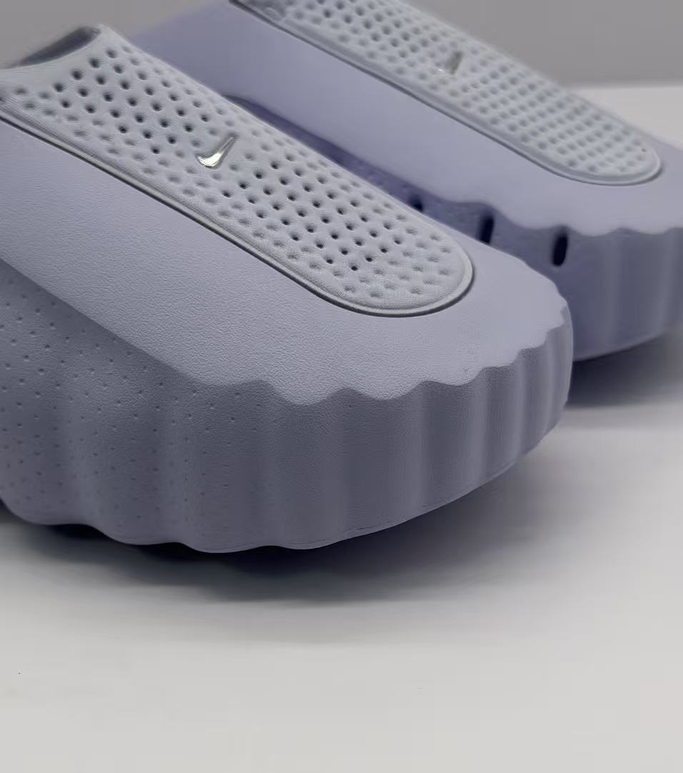 Close-up of the perforated strap, textured upper, and scalloped edge of the purple slide.