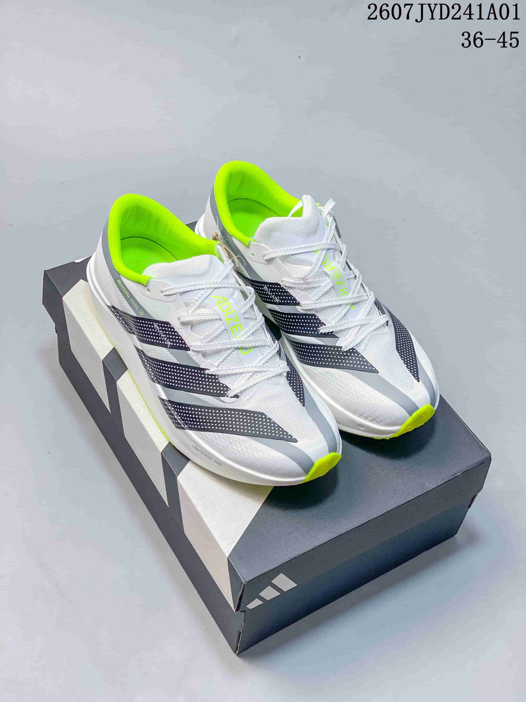 Pair of white Adidas Adizero running shoes with dark stripes and neon yellow-green accents; image displays the size range 36–45.