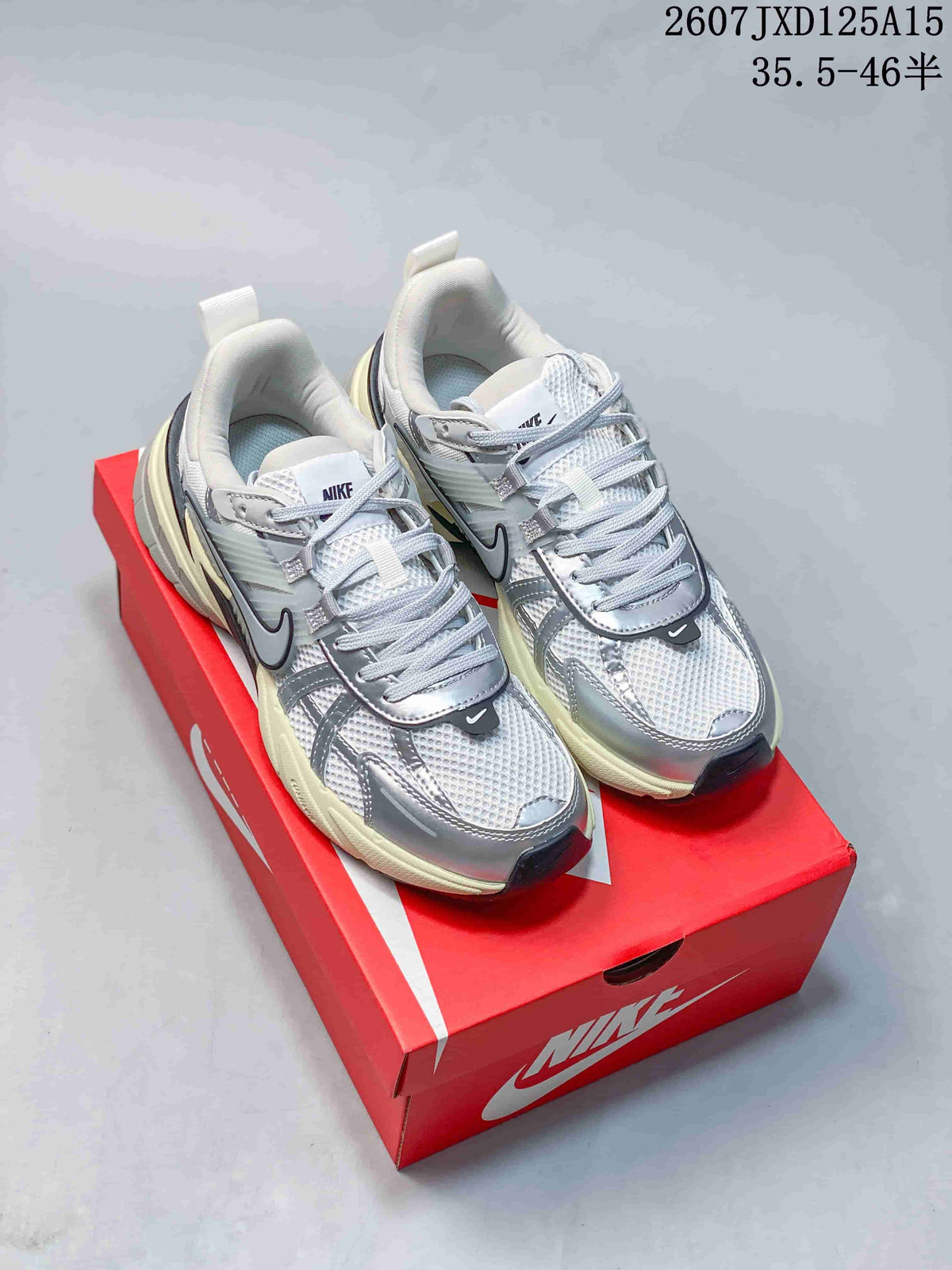 Pair of silver and white Nike V2K sneakers with contrasting dark and pale yellow outsole accents.